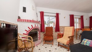 A living room with a fireplace, wicker chairs, a sofa, and a television. - Villa Mausi in Chiclana de la Frontera (Chiclana de la Frontera)