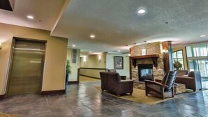 A spacious lobby with a stone fireplace, leather seating, and a large door. - 1 BDRM Condo - Great location - Hot tub and pool (Fernie)