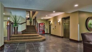 A hotel lobby with a staircase, a reception desk, and an elevator. - 1 BDRM Condo - Great location - Hot tub and pool (Fernie)