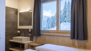 Une salle de bain moderne avec un grand miroir, un lavabo et une fenêtre avec des rideaux.
