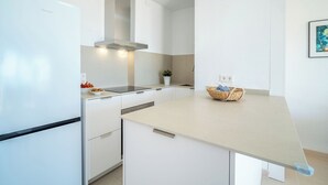 A modern kitchen with white cabinetry, a stainless steel range hood, and a light-colored countertop. - Apartment Xisca by Interhome (Port d'Alcúdia)