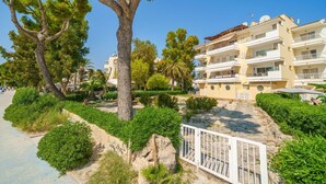 A coastal hotel with multiple balconies, a sandy beach area, and lush greenery. - Apartment Xisca by Interhome (Port d'Alcúdia)