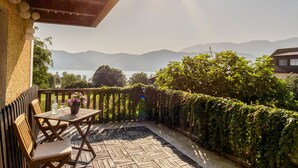 Eine Holzterrasse mit Tisch und Stühlen mit Blick auf einen See und Berge.