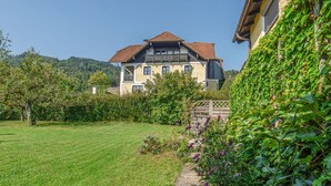 Ein zweistöckiges Haus mit Ziegeldach, umgeben von einem gepflegten Rasen und verschiedenen Pflanzen.