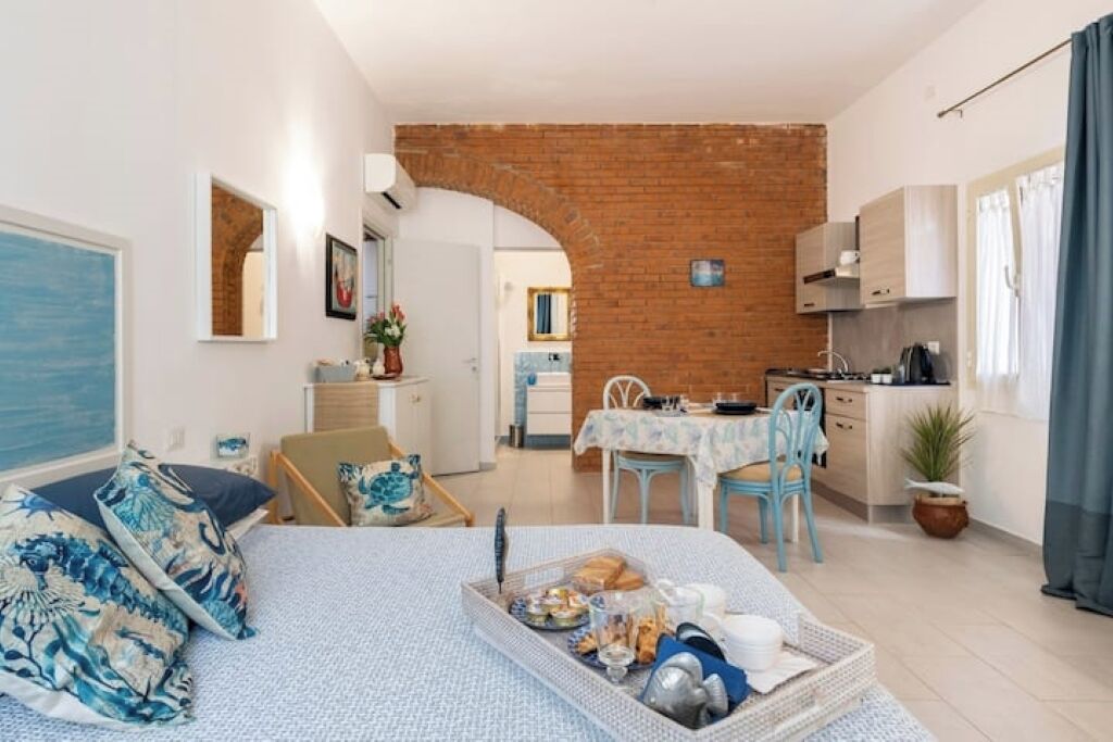 A compact apartment with a kitchen, dining area, and a bed with a breakfast tray.
