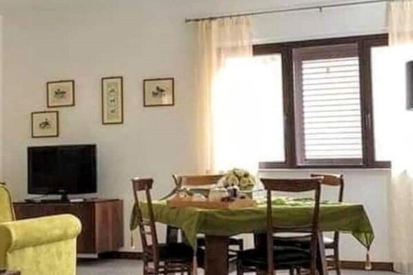 Un comedor con una mesa dispuesta para cuatro, un televisor y cuadros en la pared.