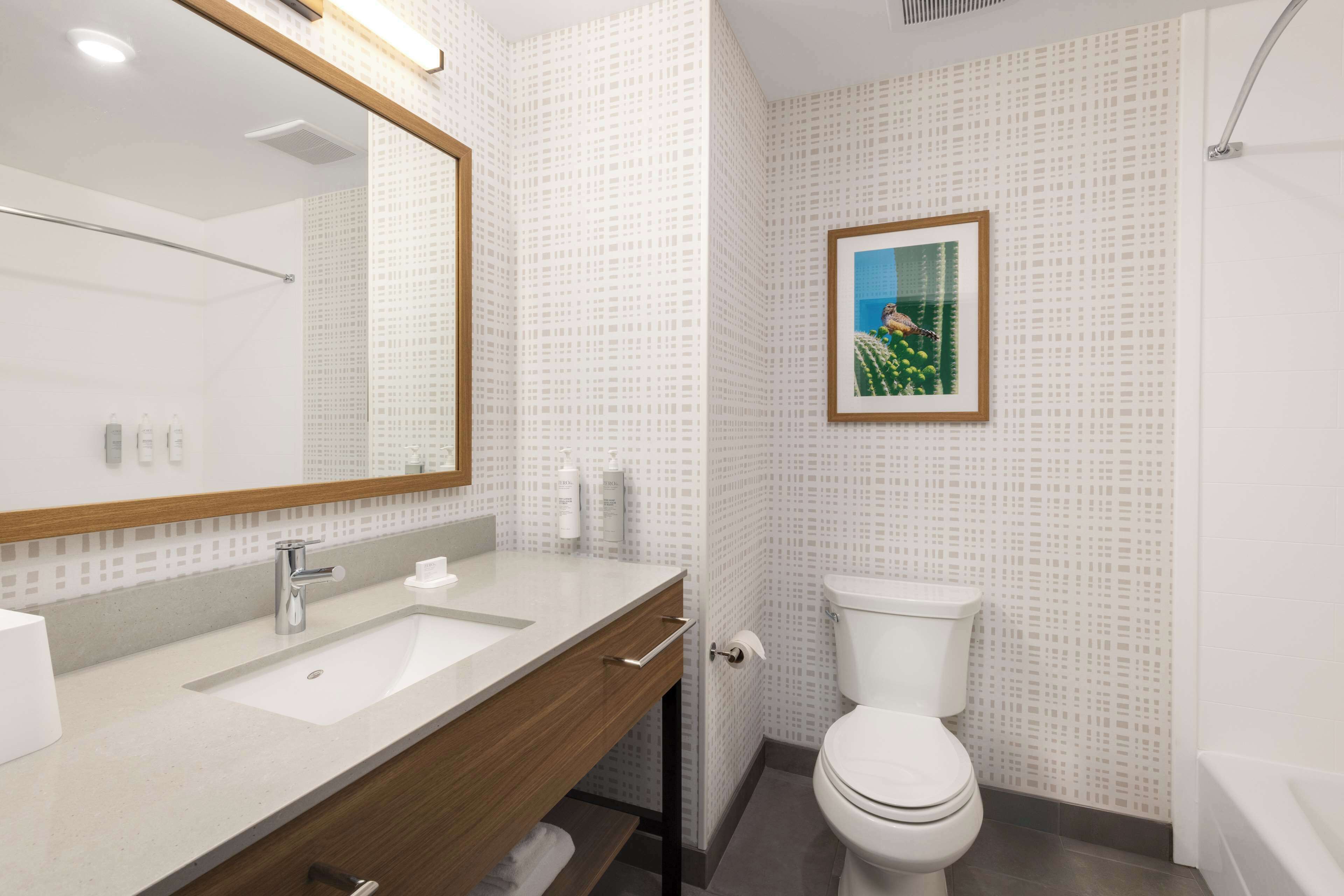 Un bany modern amb un mirall gran, un lavabo i un vàter.