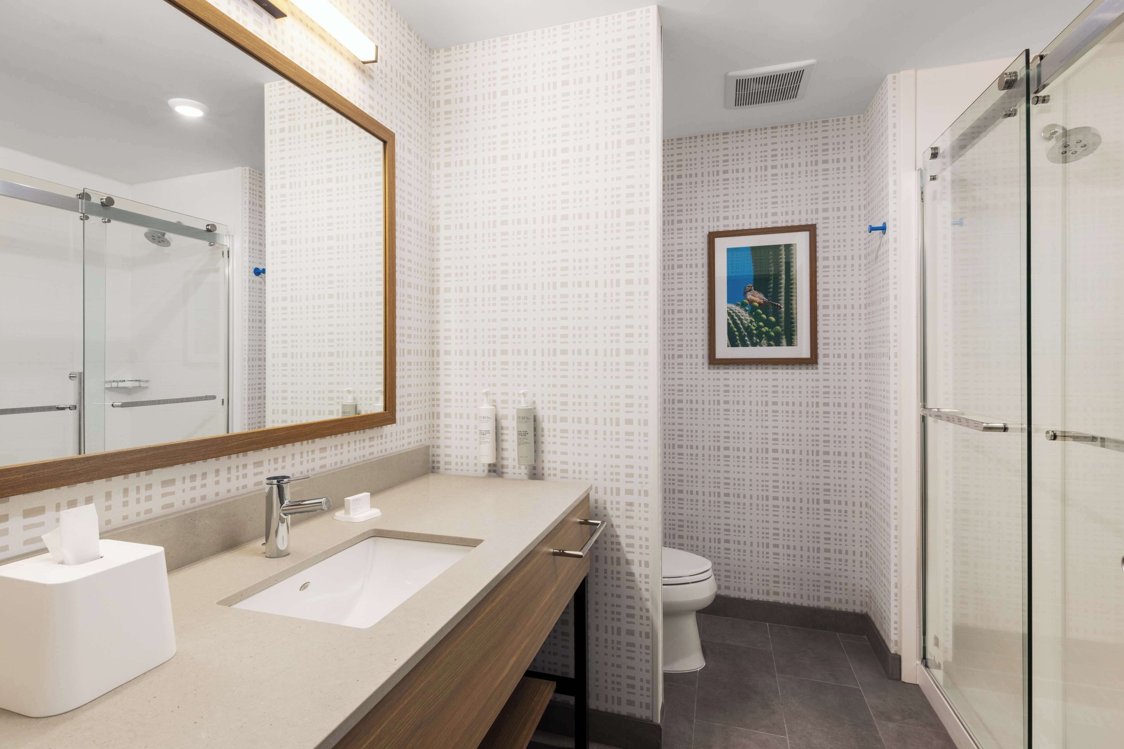 Een moderne badkamer met een grote spiegel, een wastafel en een toilet.