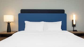 A neatly made bed with a blue headboard, two bedside tables with lamps, and a textured wall in the background.