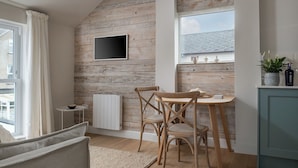 Un comedor acogedor con una pared de madera rústica, una mesa con sillas, un radiador y una ventana con vistas a la ciudad.