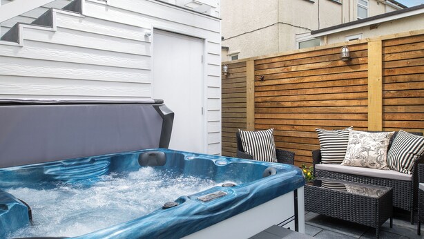 Un jacuzzi con cerco de madera y zona de estar con cojines.