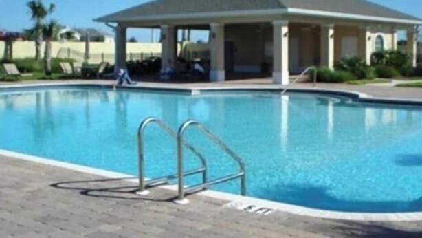 Une piscine dotée d’un pavillon abrité, d’une eau d’un bleu cristallin et d’une terrasse dallée.
