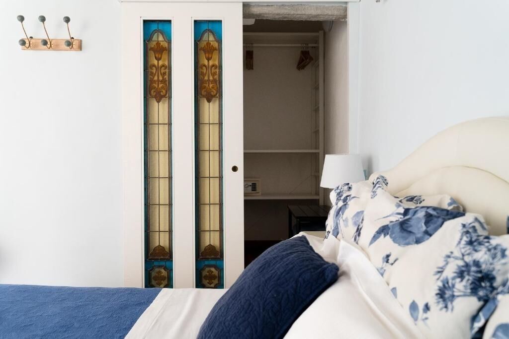 A bedroom with a bed, a wardrobe with a decorative door, and a coat rack.