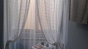 Een kamer met een stoel, een tafeltje en een raam met dunne gordijnen.