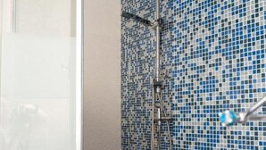 Een douche met een betegelde mozaïekwand.