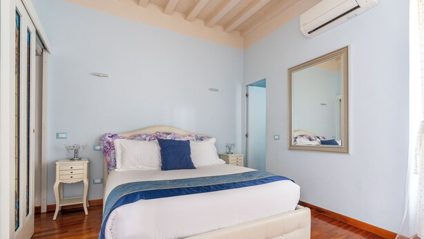 Een slaapkamer met een bed, nachtkastjes, een spiegel en een houten vloer.