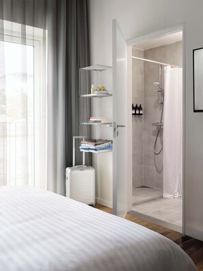 A hotel room with a bed, a white radiator, a storage rack with toiletries, a shower area, and a view of the outdoors. - Studio Apartment for 2 (København)