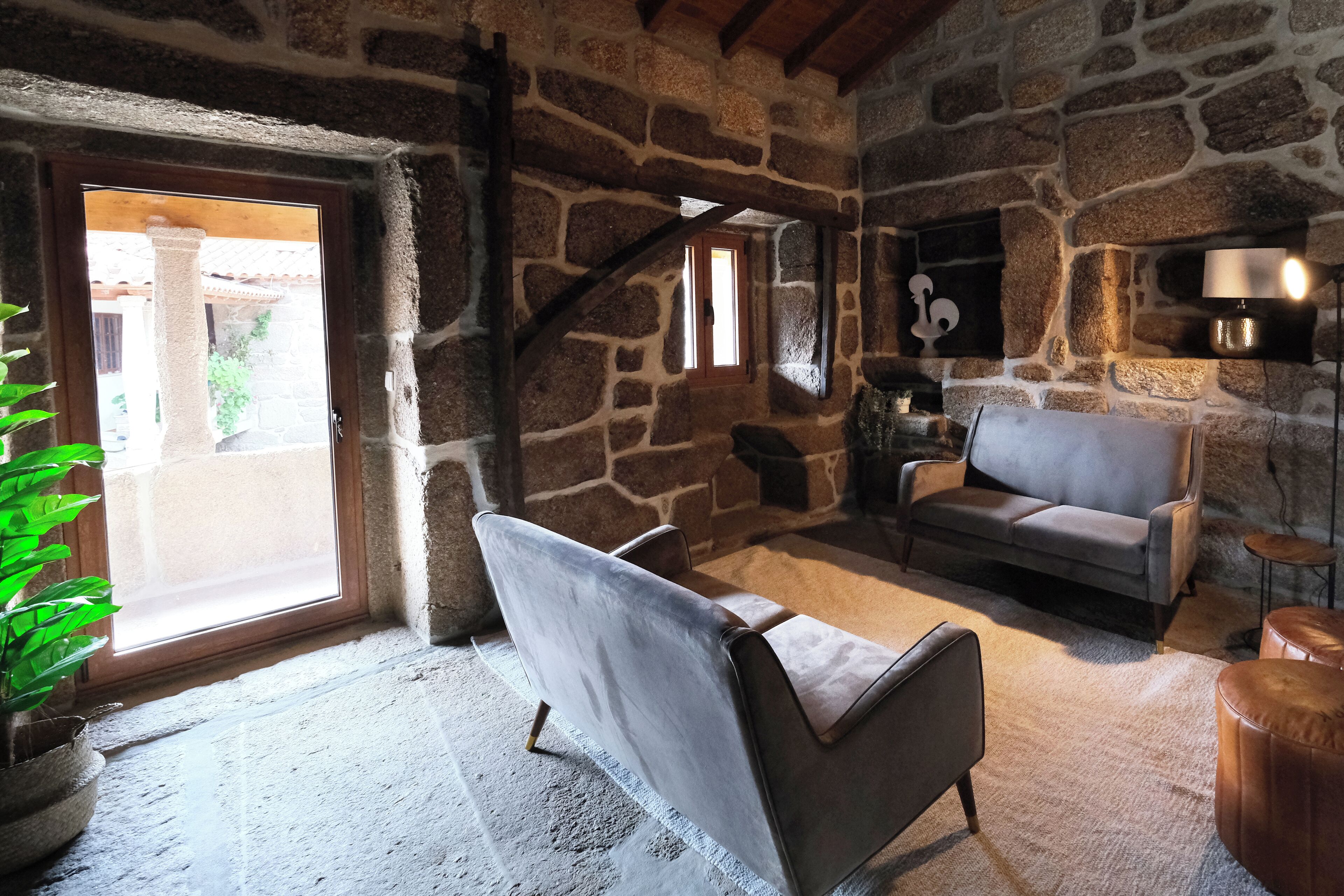 A stone-walled room with a sofa, a chair, and a small table.