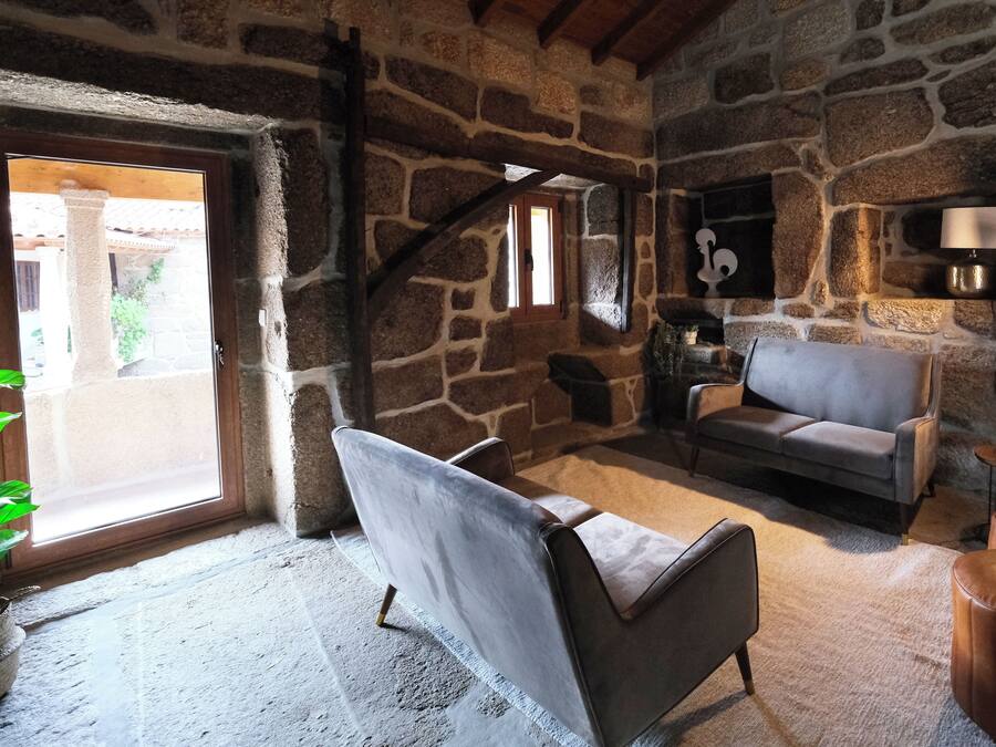A stone-walled room with a sofa, a chair, and a small table.