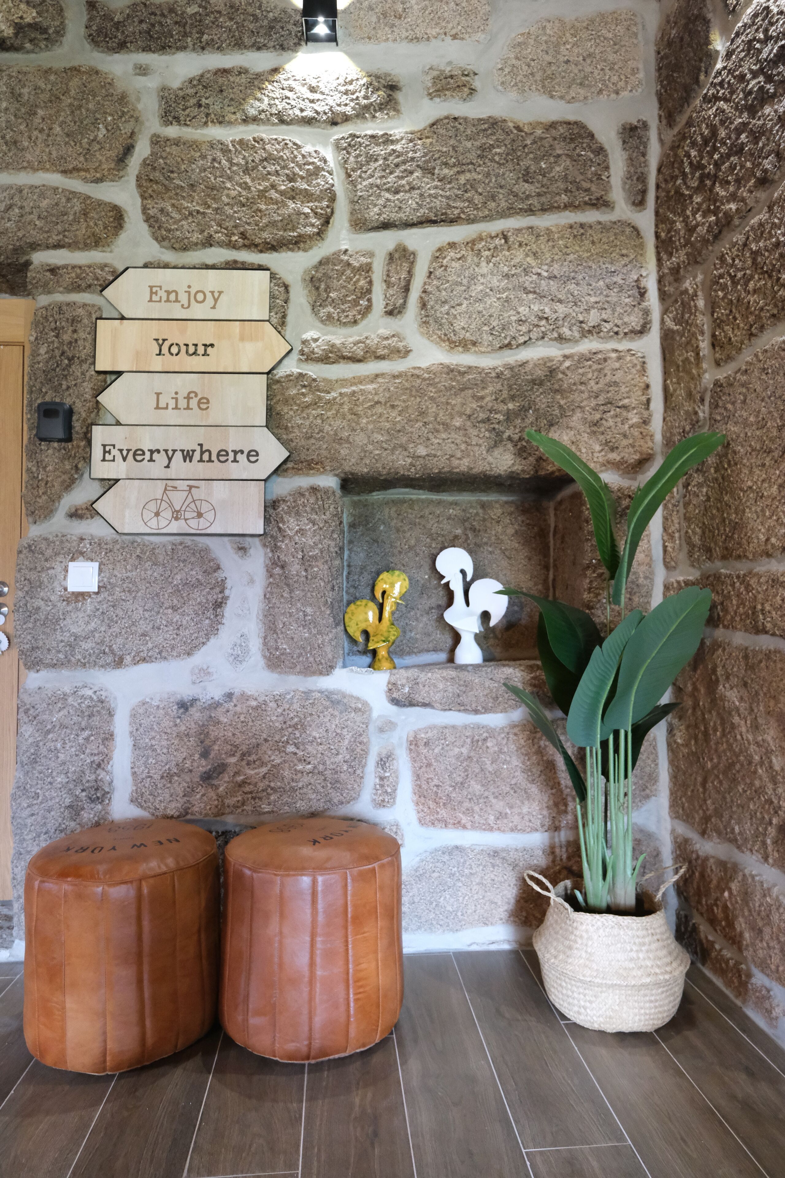 A stone wall with a fireplace, wooden signs, and two leather poufs.
