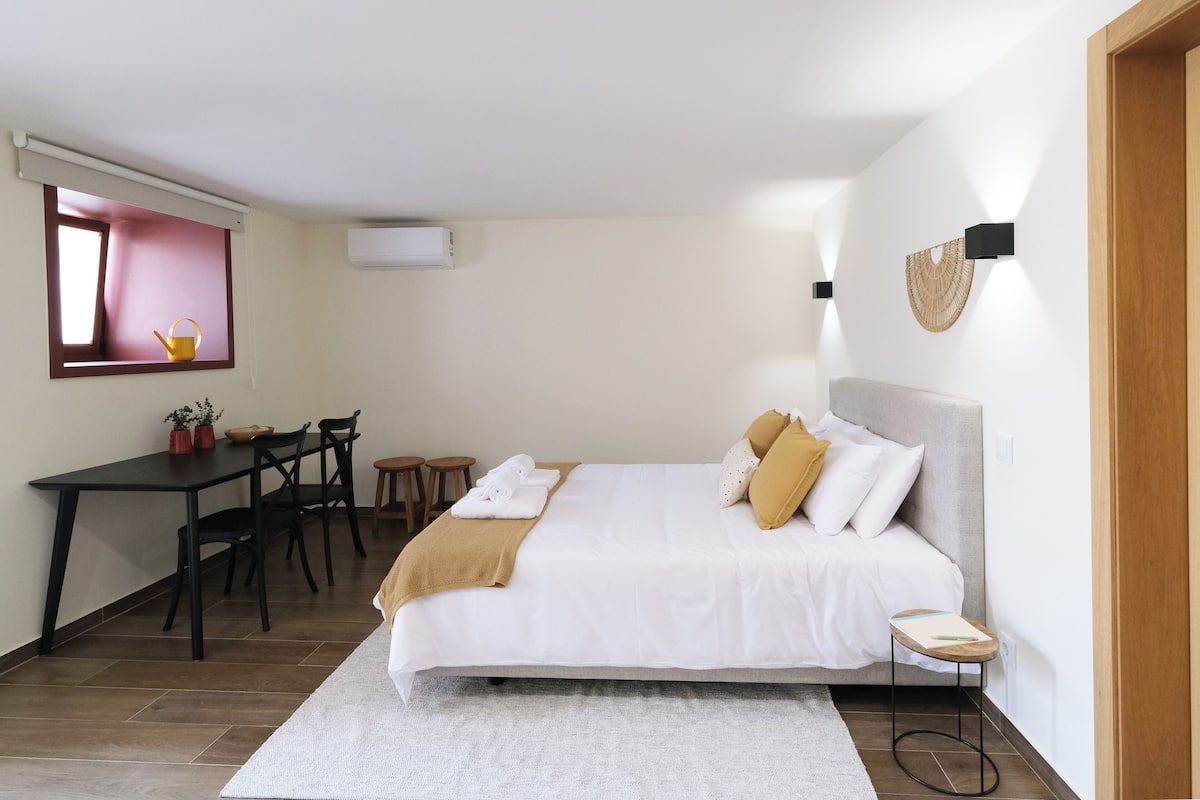 Una camera da letto con un letto, un comodino e una scrivania con sedie.