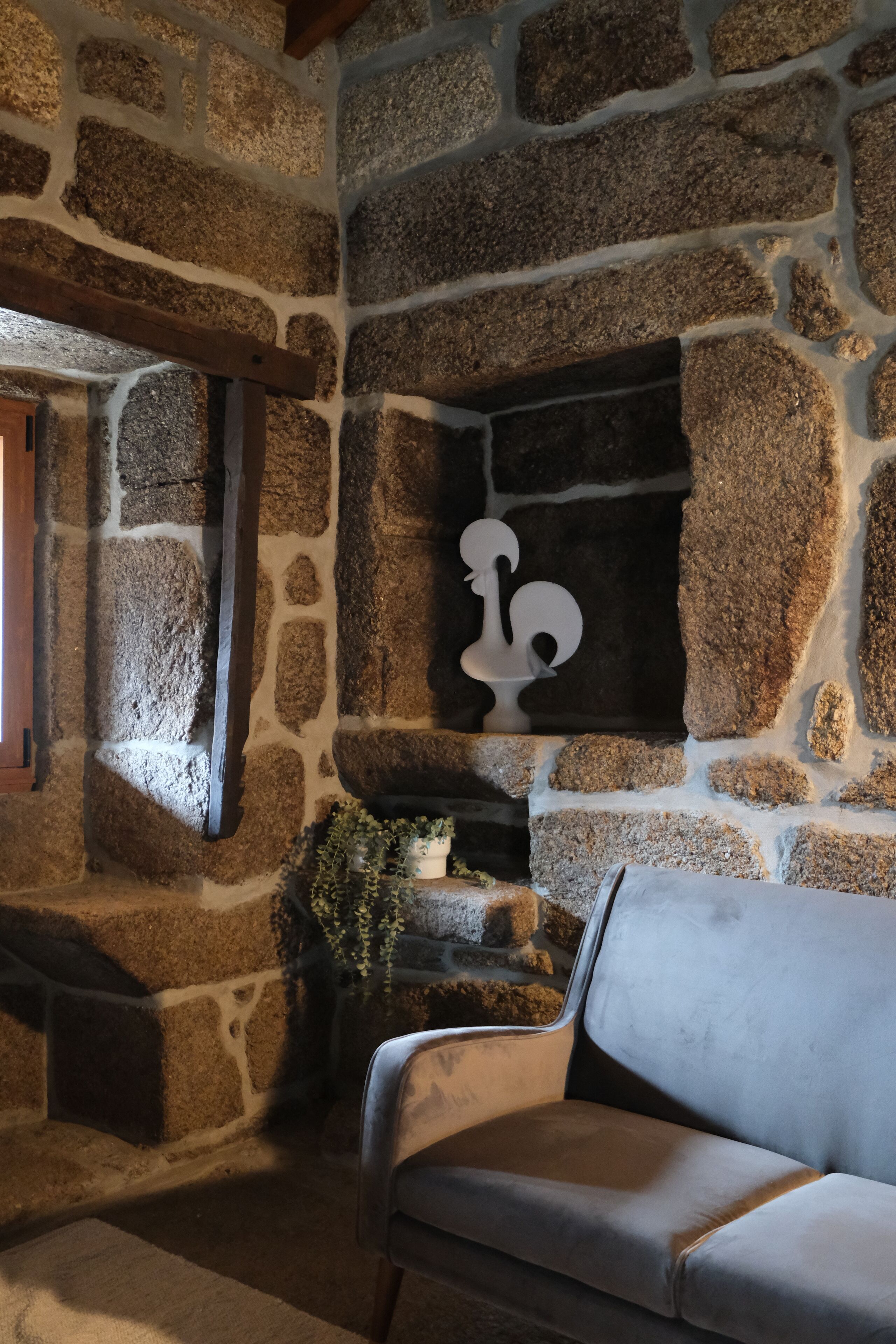 A stone wall with a fireplace, a sofa, and a decorative item.