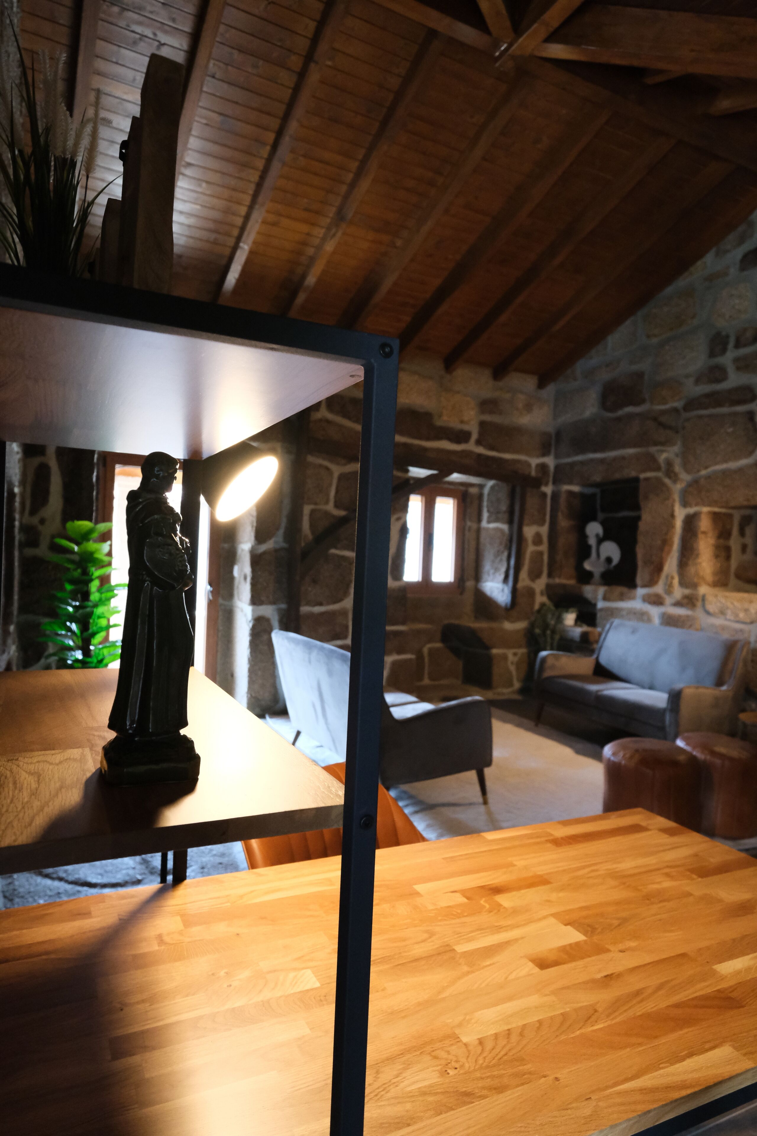 A rustic stone interior with a wooden table and a statue.