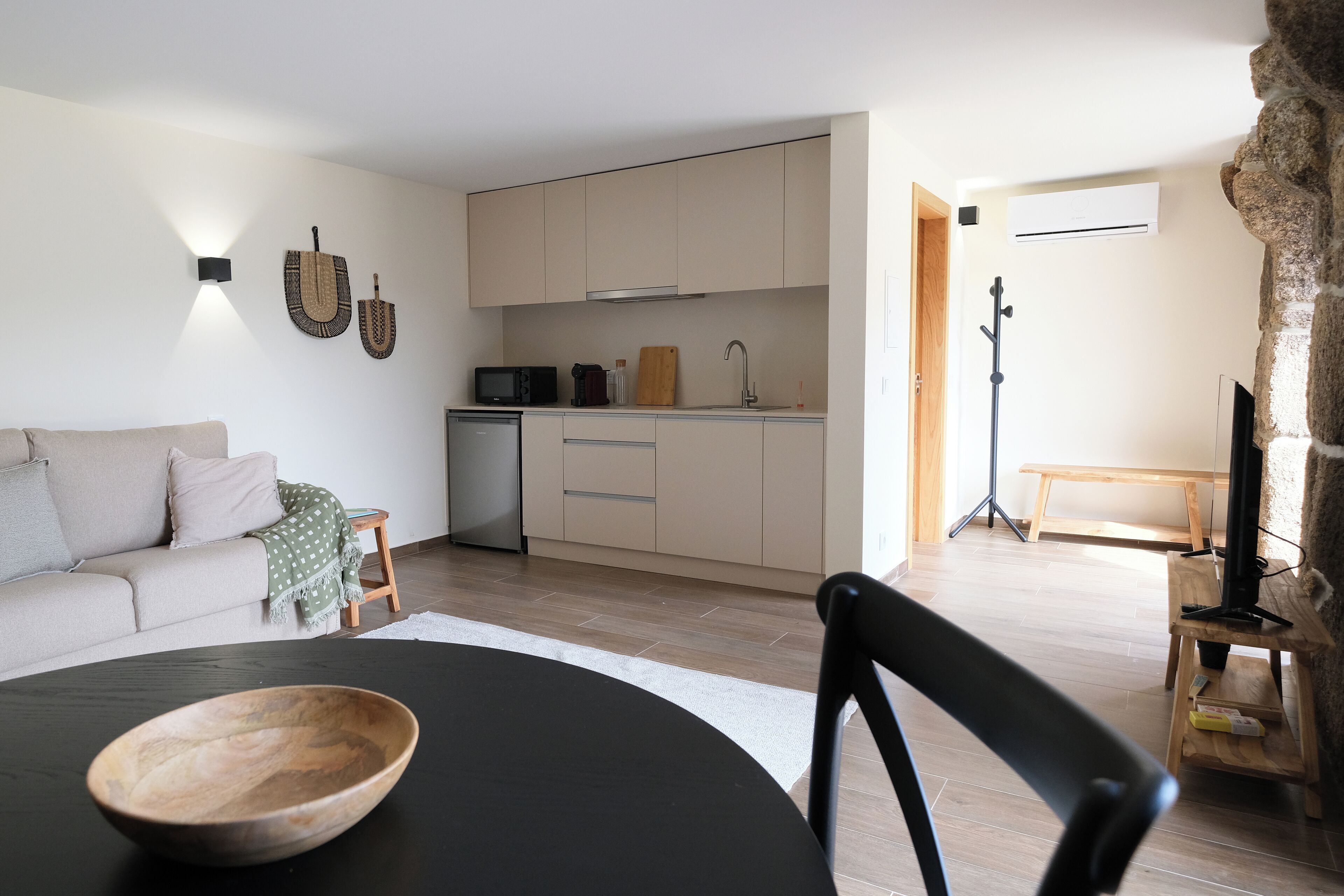 A modern living room with a black dining table, a wooden bowl, and a black chair.