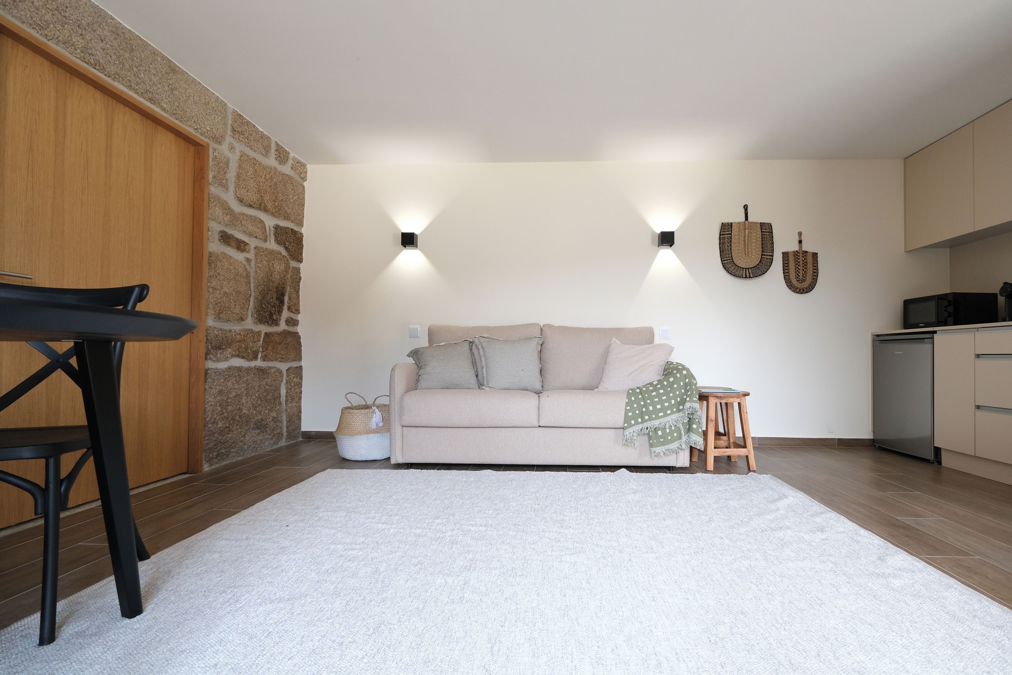 A modern living room with a sofa, a dining table, and a kitchen area.