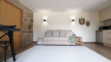 A modern living room with a sofa, a dining table, and a kitchen area.