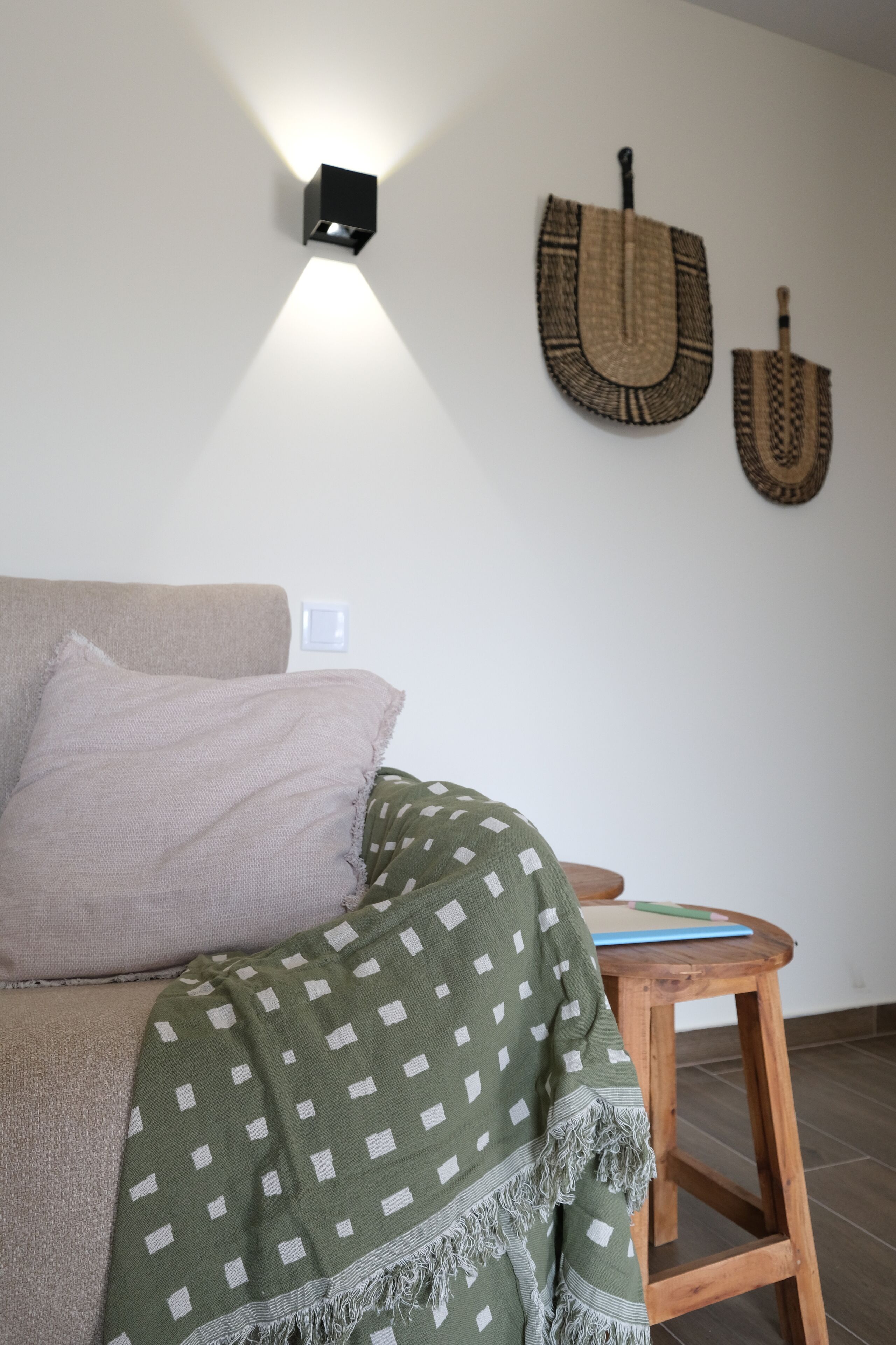 A room with a bed, a wooden stool, and wall-mounted wall art.