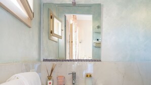 Une salle de bain avec un meuble-lavabo blanc, un miroir, un évier, un bidet et un porte-serviettes.