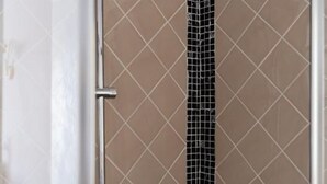 A bathroom with a tiled wall and a metal faucet. - Marty Violet - Milù Holidays Firenze
 (Firenze)