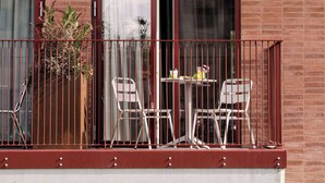 Ein Balkon mit zwei Stühlen, einem kleinen Tisch, einem Blumentopf und einer Ziegelwand.