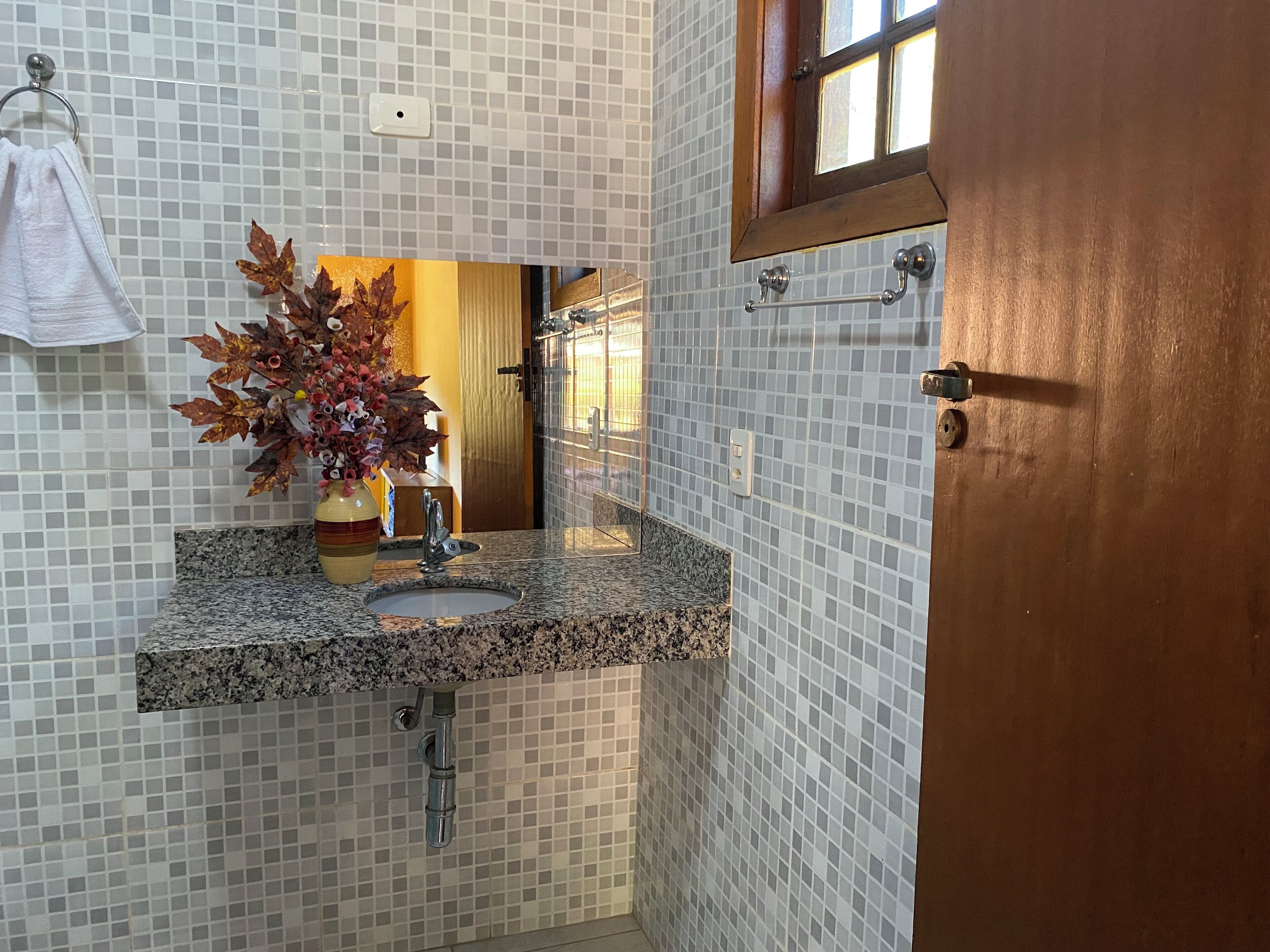 Un baño con encimera de granito, lavabo, espejo y puerta de madera.
