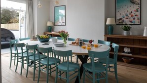 A dining area with a round table, teal chairs, and a breakfast setting including fruits, bread, and drinks. - Camellia House, indulge in luxury at our Victorian gem in the heart of Abersoch! (Pwllheli)