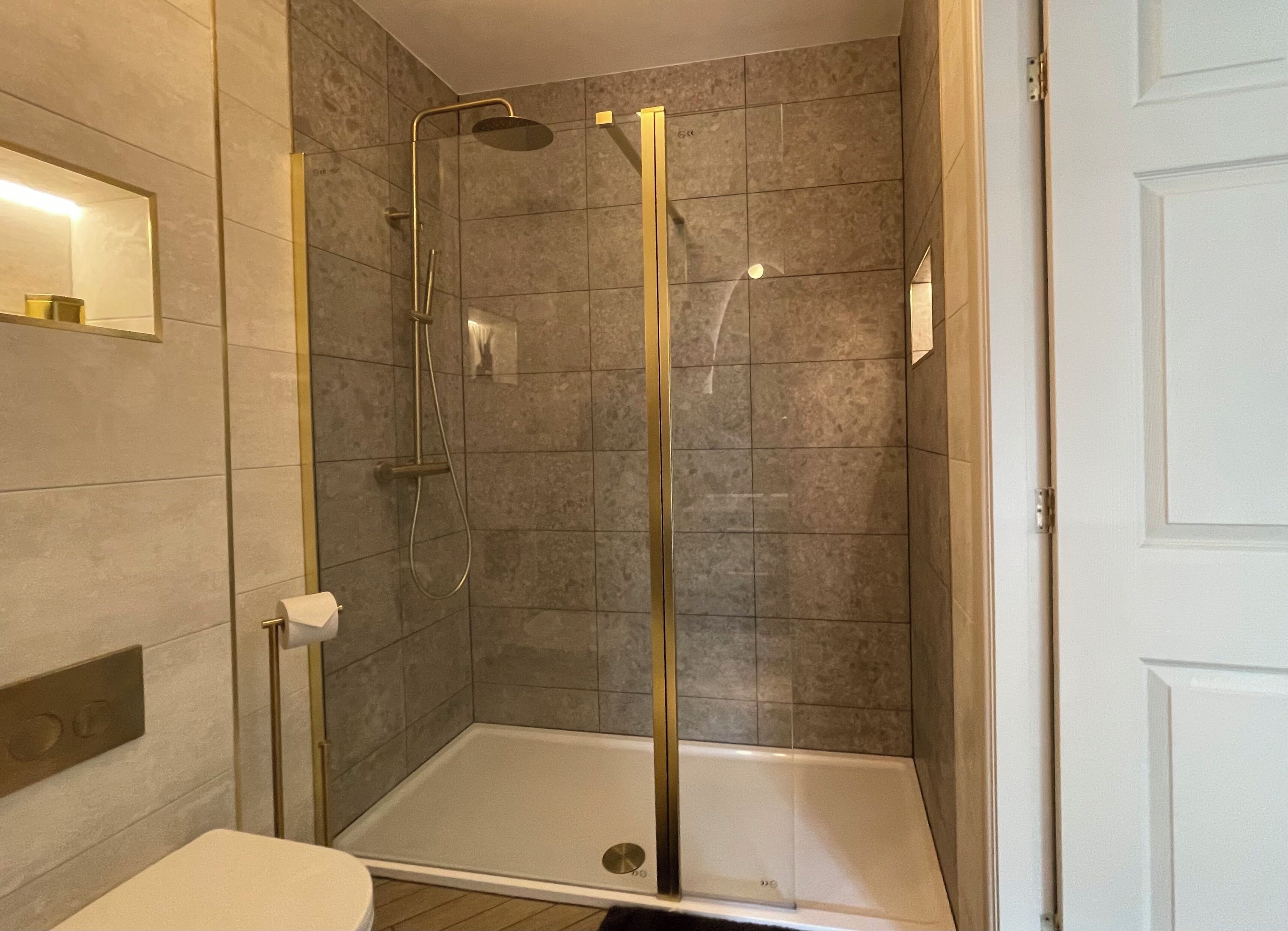 A modern bathroom with a glass-enclosed shower, a toilet, and a sink.