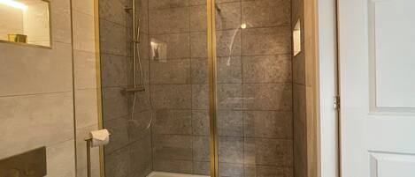 A modern bathroom with a glass-enclosed shower, a toilet, and a sink.