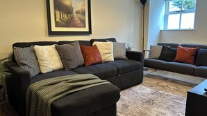 A living room with two sofas, a framed painting, and a floor lamp. - Cozy Manchester Hideaway With 2 Bedrooms (Manchester)