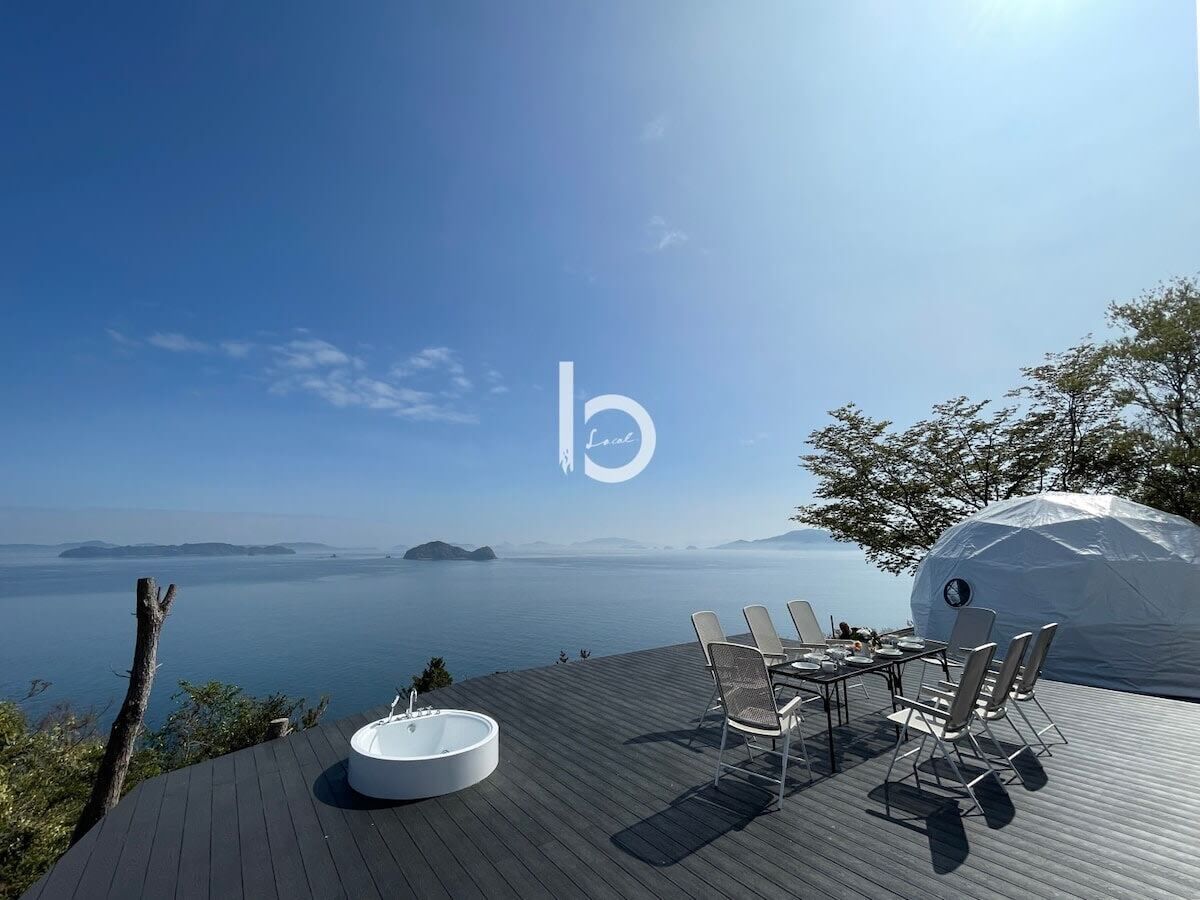 Eine Terrasse mit einem runden Tisch und Stühlen mit Blick auf ein Gewässer.