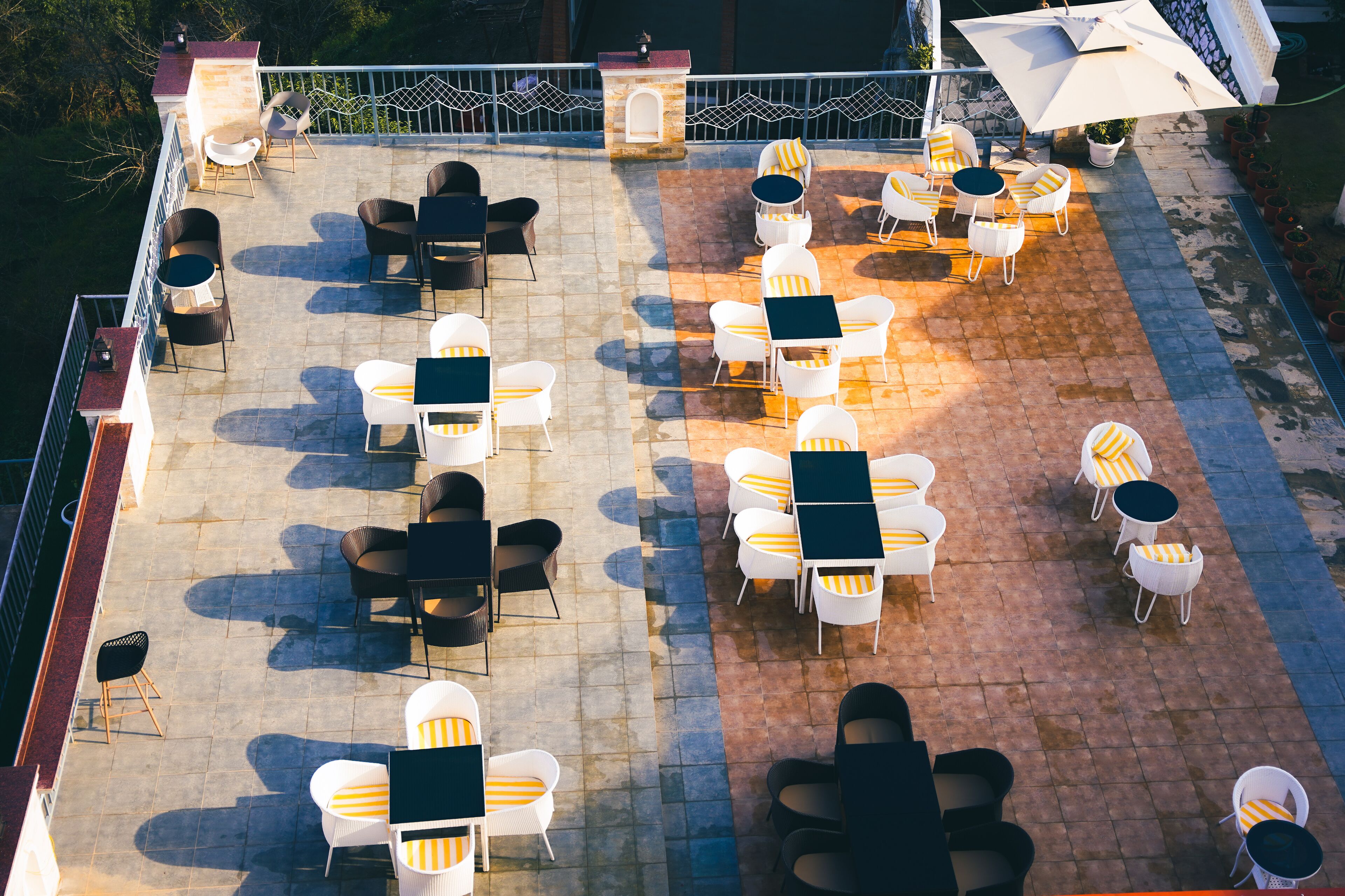 An outdoor patio with multiple tables and chairs, some with umbrellas.