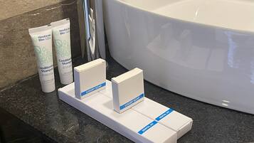 Een badkamermeubel met een groot bad, twee tubes Himalayabliss conditioner, en dozen met de tekst 'Luxe Zeep' en 'Tandenborstelsset'.