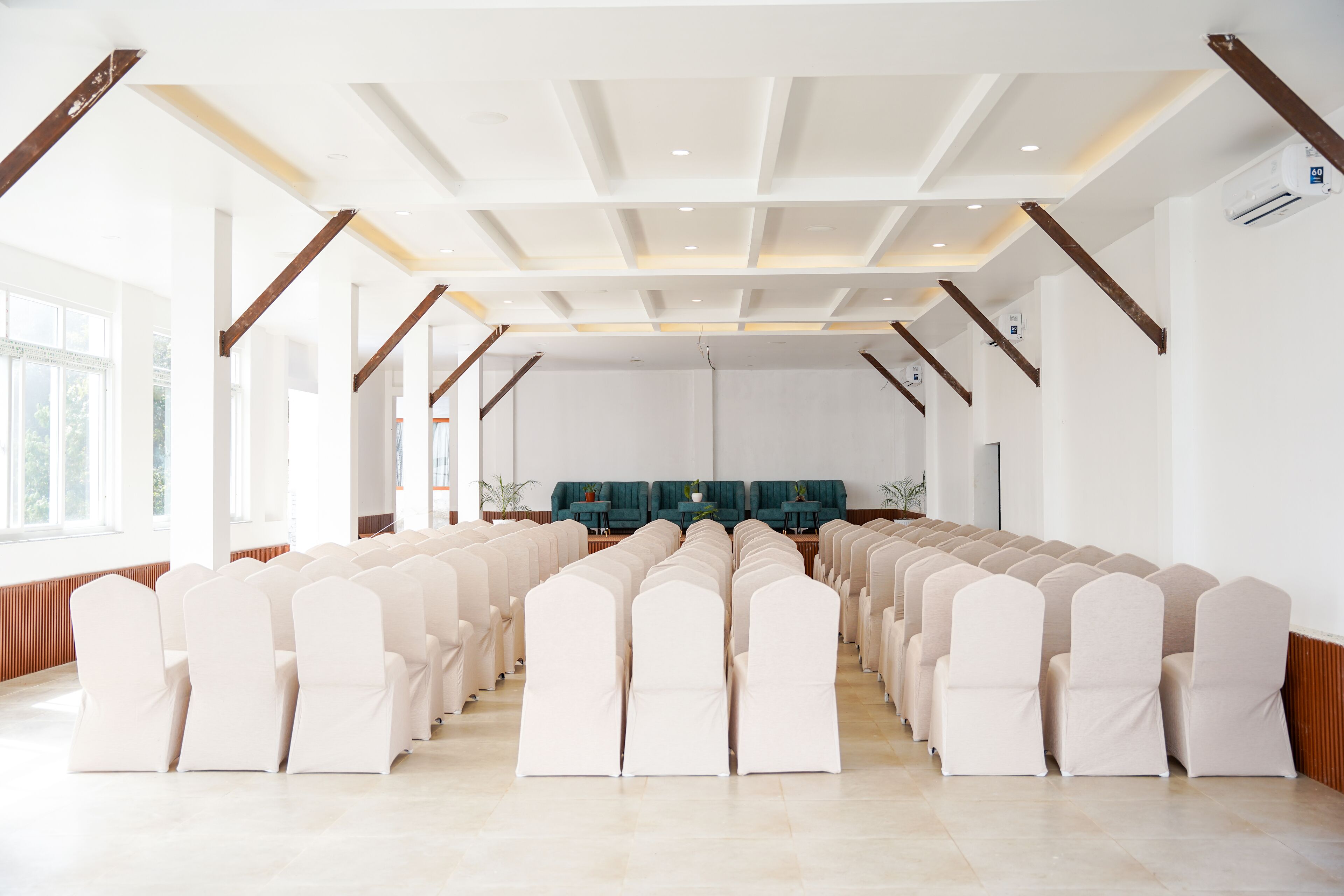 A spacious hall with rows of chairs, a high ceiling with wooden beams, and large windows.