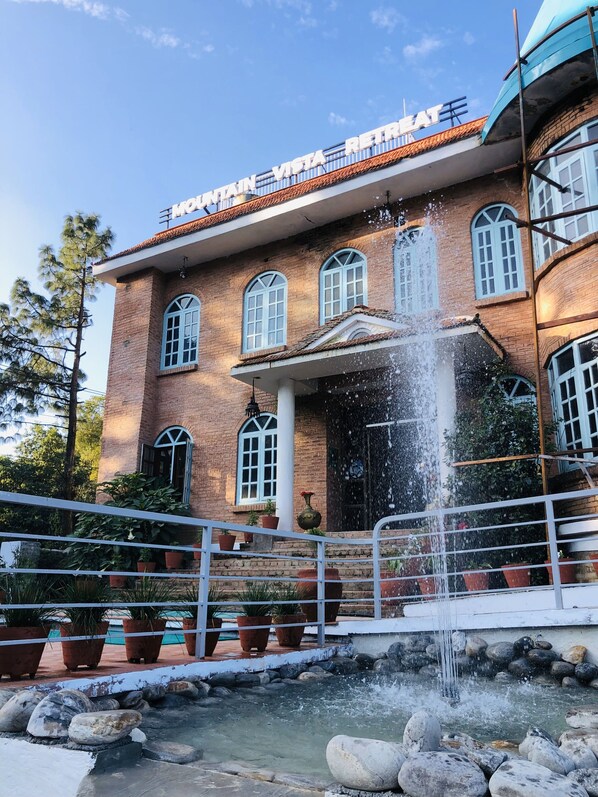 A building with a sign reading "MOUNTAIN VISTA RETREAT" and a water feature in front.