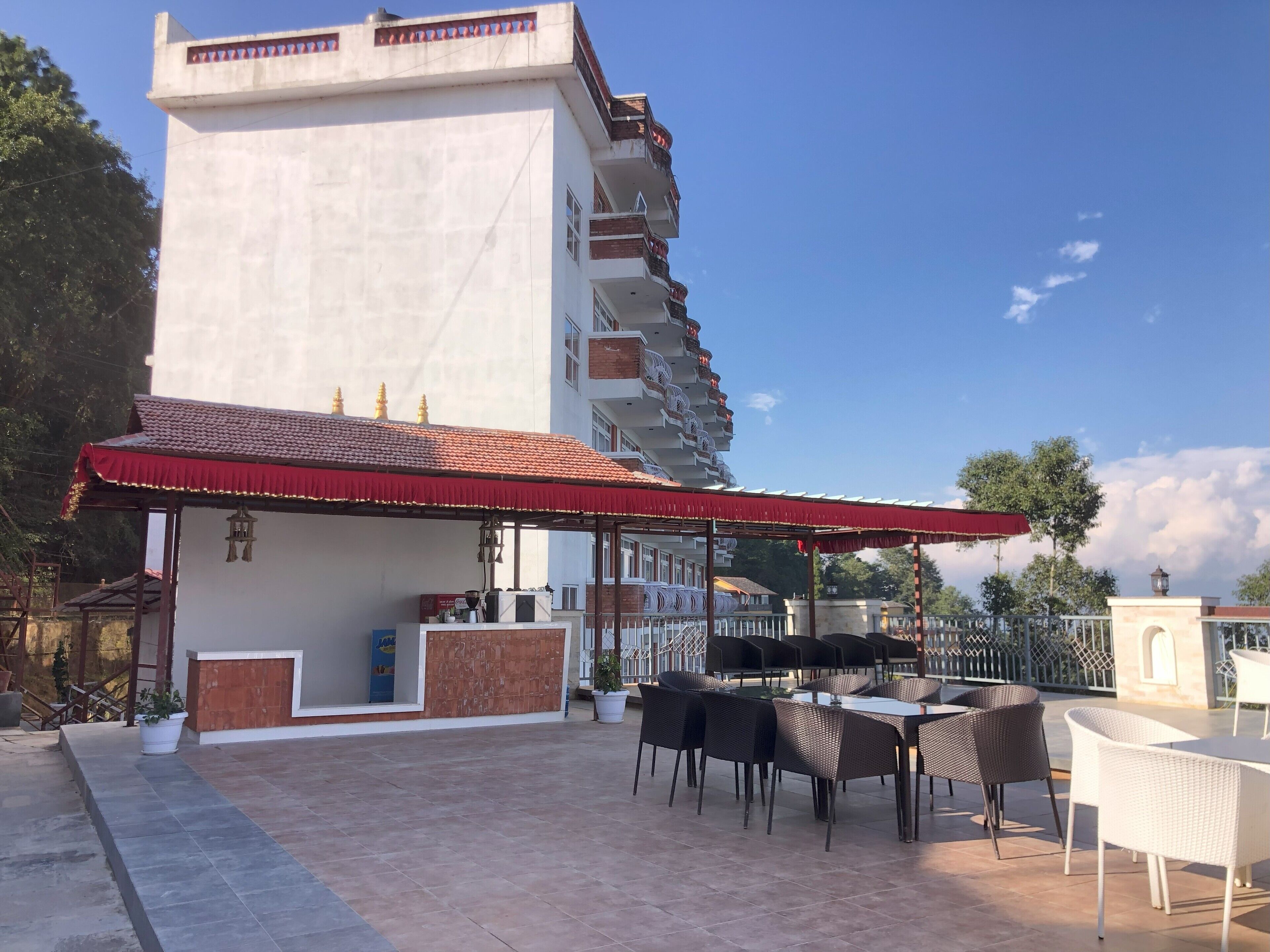 A hotel with a terrace featuring outdoor seating and a red awning.