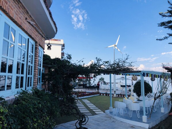 A courtyard with a wind turbine, outdoor seating, and a pergola. - Mountain Vista Retreat (Baluwapati Deupur)