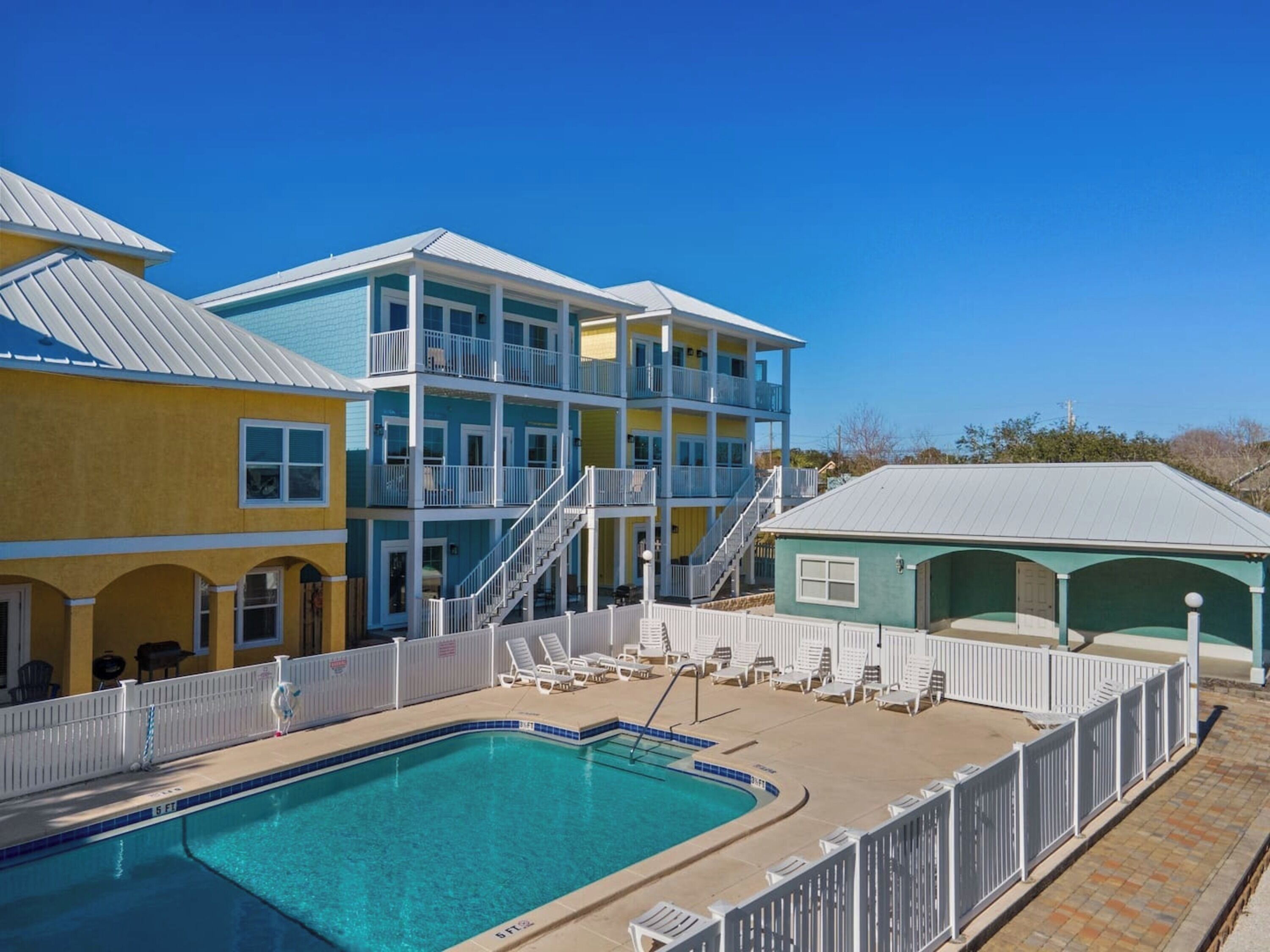 A multi-story hotel with a pool area, including a pool, lounge chairs, and a staircase.