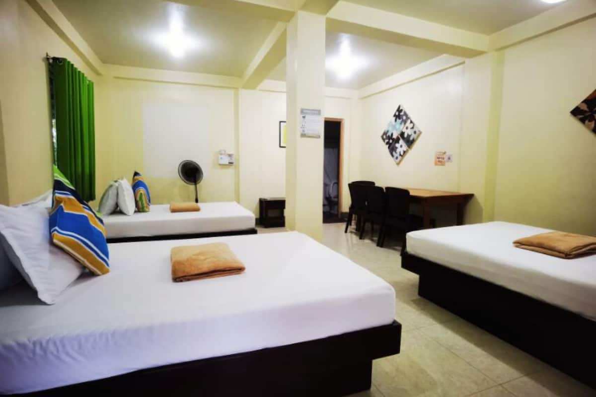 A hotel room with two beds, a desk, and a chair.