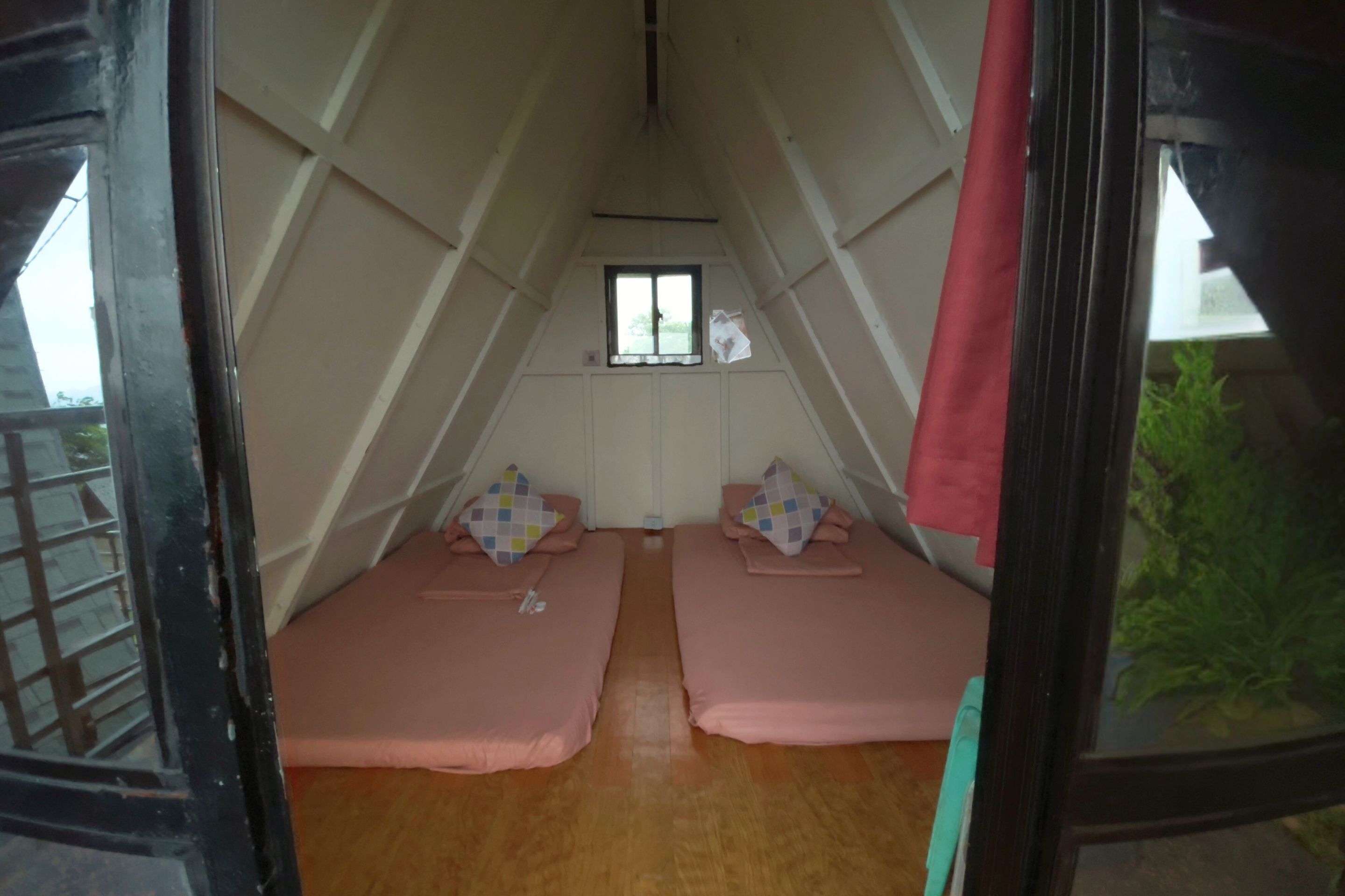 A room with two beds, a window, and a door.