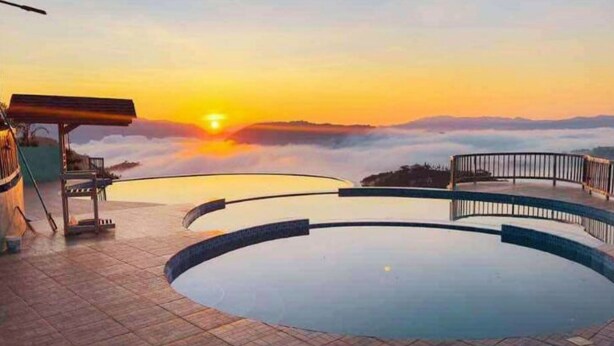 A circular pool with a sunset view, a wooden deck, and a metal railing. - Viewscape Nature Park Tanay powered by Cocotel (Tanay)